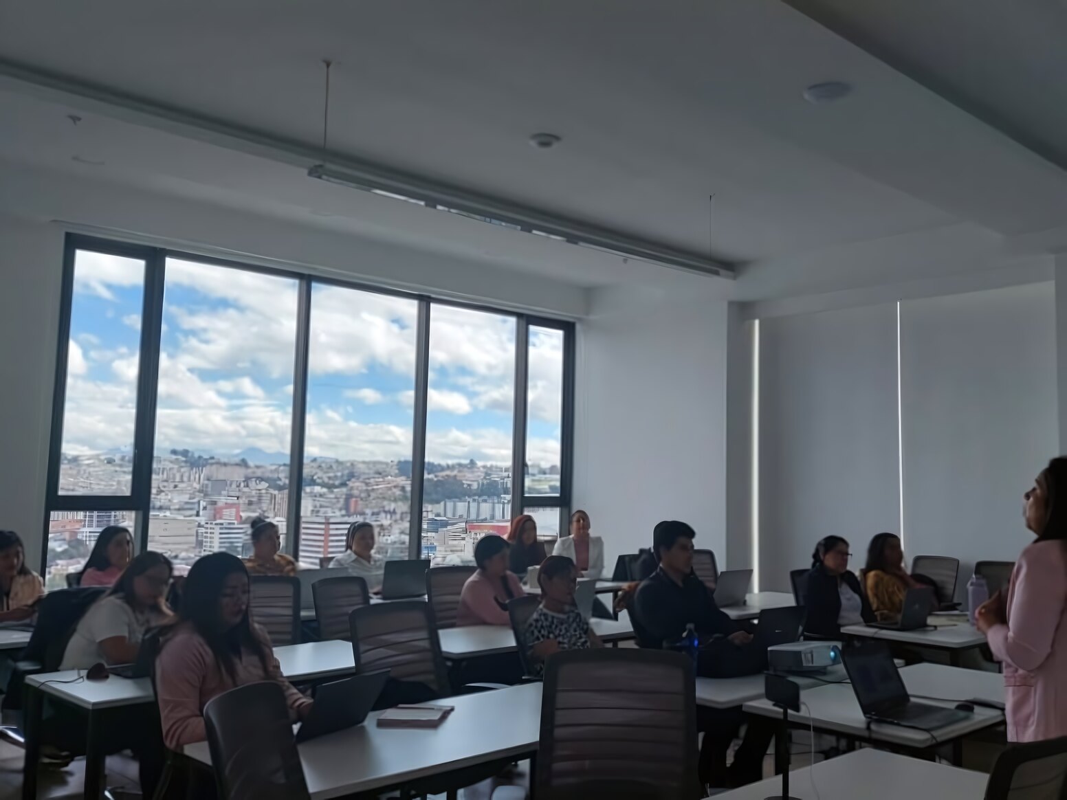 Aula con participantes trabajando en sus laptops durante una sesión de capacitación en Quito